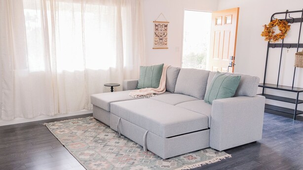 A modern living room with a grey sectional sofa, a patterned rug, and a decorative wreath on a metal stand. - Soothing 2-bedroom house with WiFi in Vista (Vista)