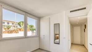 A bedroom with a large window, a wardrobe, a mirror, and a door leading to another room. - Bright Apartment 100 m from the Beach – 1st Floor (L'Escala)