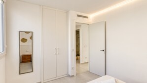 Ein Schlafzimmer mit Bett, Kleiderschrank, Spiegel und angrenzendem Badezimmer.