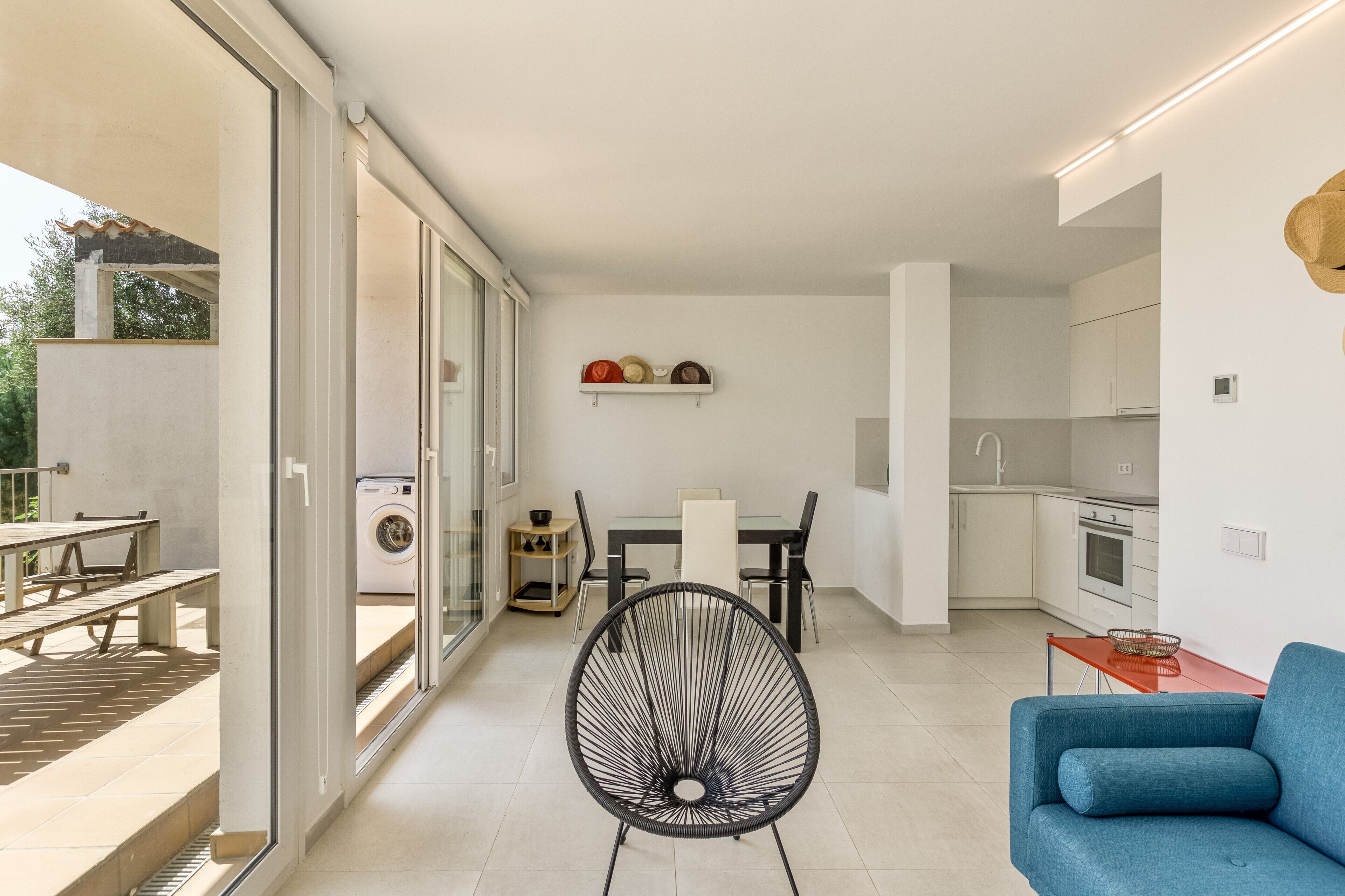 An open-plan living space with a dining area, kitchen, and a seating area with a blue sofa.