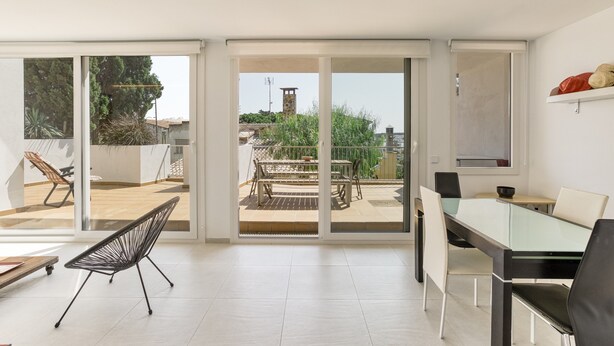 Ein modernes Interieur mit Essbereich, einem Stuhl und Blick durch Glastüren auf eine Außenpatio.