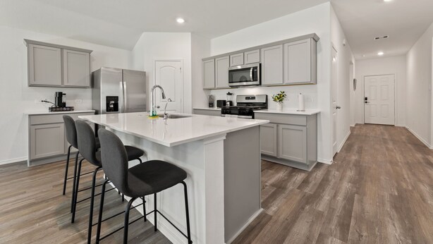 A modern kitchen with a central island, bar stools, stainless steel appliances, and light grey cabinetry. - Brand-New 4BR Magnolia Retreat · Sleeps 8 · Fast WiFi · 30 Min to Woodlands (Magnolia)
