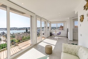 A spacious balcony with a city view, a dining area with chairs, and a kitchen area.