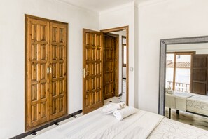 A hotel room with a bed, two wooden wardrobes, a mirror, and a window with a view.