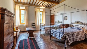 A rustic room with a four-poster bed, a wooden dresser, a bench, and a table. - Villa 'Ballati' with Shared Garden (Ville di Corsano)