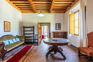 Une pièce avec un plafond en bois, une table ronde en bois, un canapé, une chaise et un buffet.