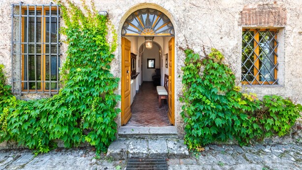A stone building with an arched entrance, a bench inside, and ivy on the walls. - Villa 'Ballati' with Shared Garden (Ville di Corsano)
