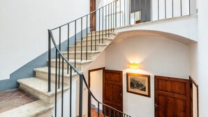 A staircase with a metal railing, a wooden door, and a wall-mounted light fixture. - Villa 'Ballati' with Shared Garden (Ville di Corsano)