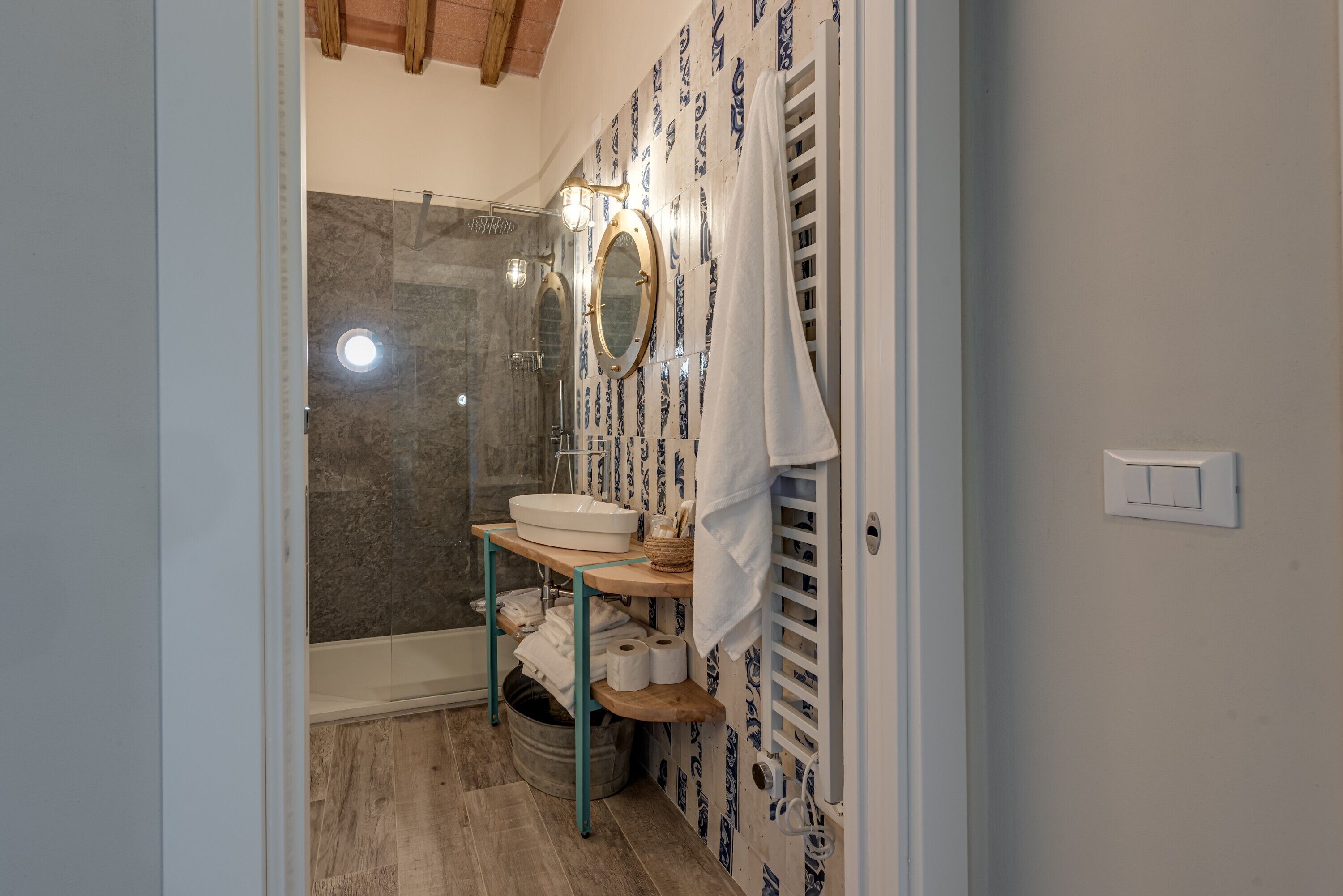 A bathroom with a shower, a sink, a mirror, and a towel rack.