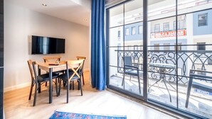 Een eethoek met een tafel en stoelen, een aan de muur bevestigde televisie en een groot raam met uitzicht op het omliggende landschap.