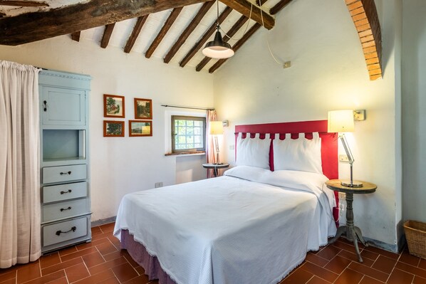 A bedroom with a bed, a dresser, a window, and a lamp.