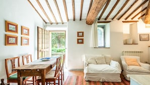 Una habitación con una mesa de comedor de madera, sillas, un sofá y una ventana.