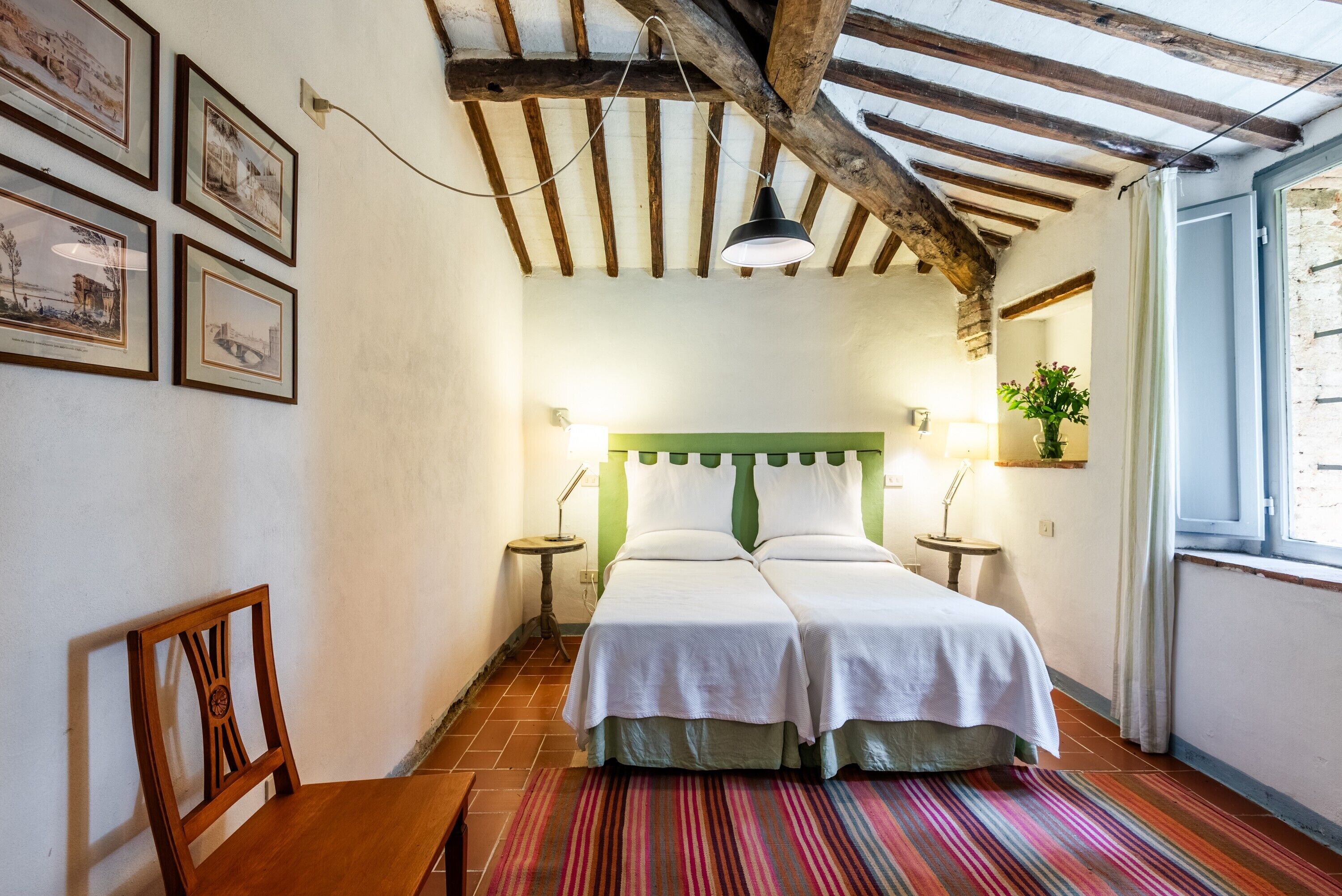 Una habitación con cama, una silla, una lámpara y una ventana.