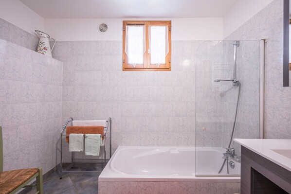 Un baño con bañera, ducha y ventana.
