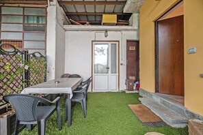 A small outdoor patio with a table and chairs, a wooden door, and a fenced area.