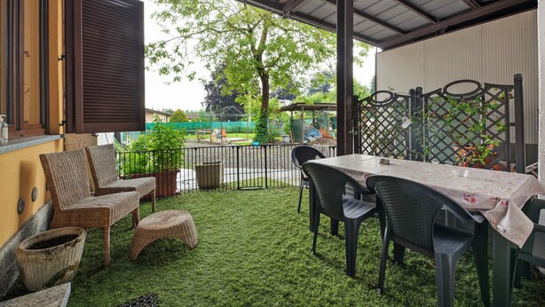 Une terrasse extérieure avec une table, des chaises et un espace abrité.