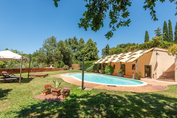 Un jardin avec une piscine, un patio couvert et un escalier menant à la maison.