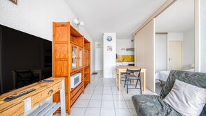 Un espacio habitable compacto con televisor, armarios de madera, una mesa de comedor y un sofá.