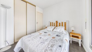 Un dormitorio con cama, mesita de noche, lámpara y armario.