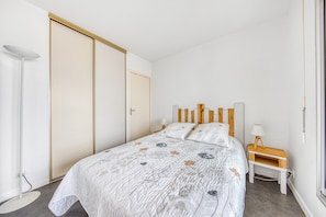 A bedroom with a bed, bedside table, lamp, and a wardrobe.