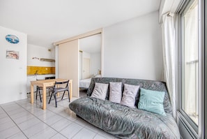 A compact living space with a sofa, a dining table, and a kitchen area.