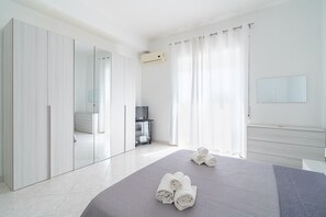 Ein modernes Schlafzimmer mit Bett, Kleiderschrank, Spiegel und Fernseher.