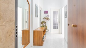 Ein Flur mit einer hölzernen Sitzbank, einem Blumentopf und einer Tür mit Messinggriff.