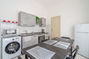 Een functionele keuken met een wasmachine, magnetron, fornuis en koelkast.