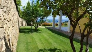 Un mur de pierres, une pelouse bien entretenue et une vue sur la mer.