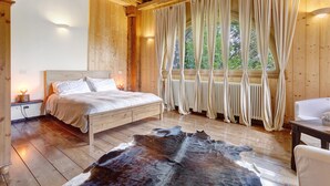 Een houten kamer met een bed, een kleden van runderleer en gordijnen.