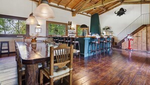 Een rustiek interieur met een houten eettafel, barstoelen, een trap en een stierenkop decoratie.
