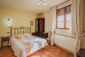 Una camera da letto con un letto, un comodino, un armadio e una finestra con tende.