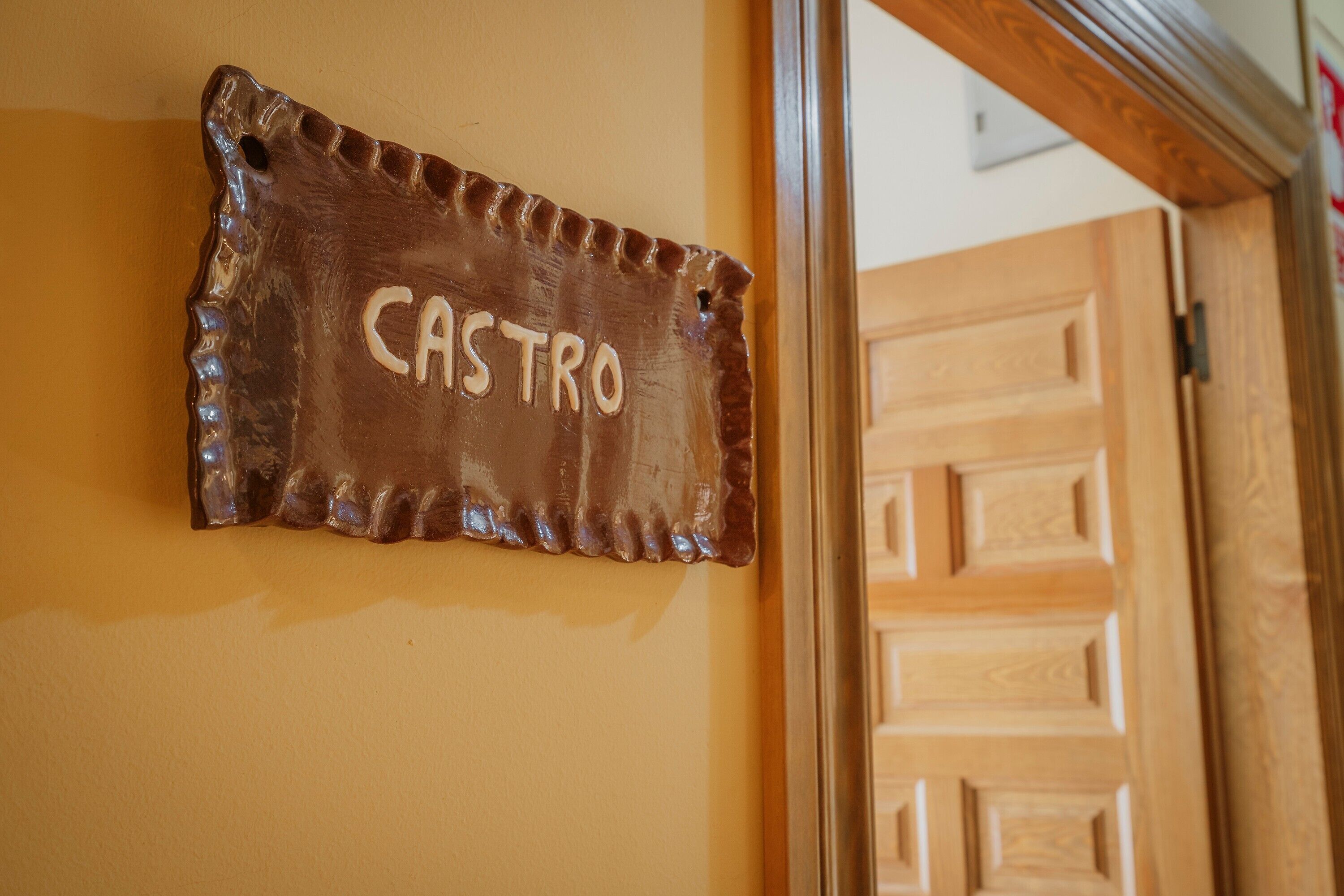 Een rustiek bord met de tekst 'CASTRO' op een structuurmuur.