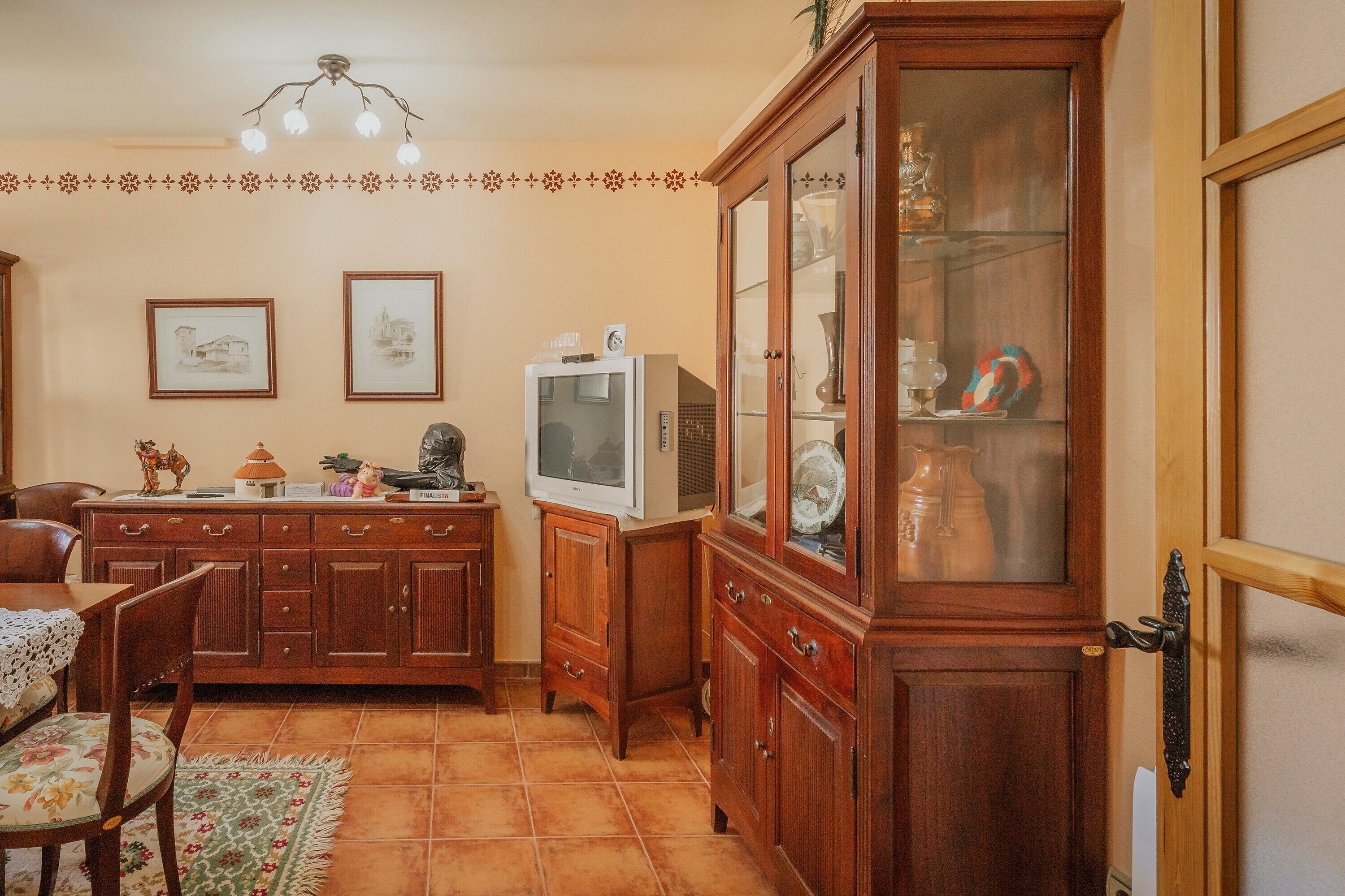 Un comedor con armarios de madera, un televisor y cuadros en la pared.