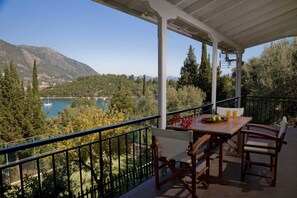 A balcony with a table and chairs overlooking a lake and mountains.