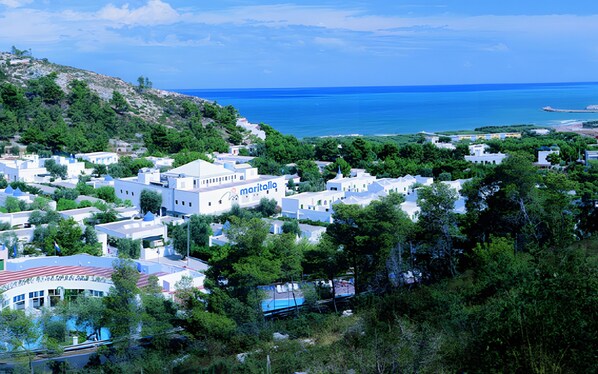 Un pueblo costero con edificios blancos, un puerto deportivo y vistas al mar.