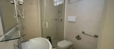 Un baño con lavamanos, inodoro, bidé y ducha con mampara de vidrio.