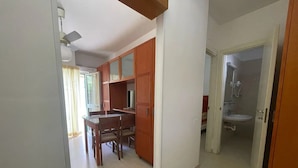 Un pasillo con comedor, armarios de madera y un baño con lavamanos y ducha.