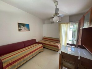 Una habitación con cama, sofá, mesa y ventilador de techo.