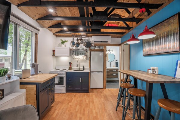 Una cocina con vigas de madera, encimera de madera y taburetes de bar.