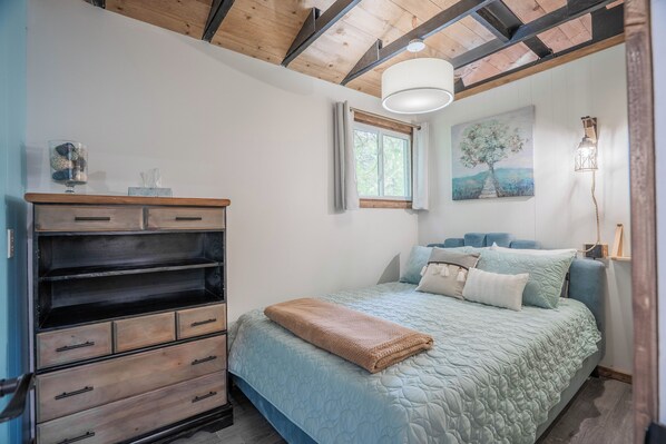 A bedroom with a bed, a dresser, a window, and a painting on the wall. - the Great Lakes Cabin at Sauble Beach (Sauble Beach)