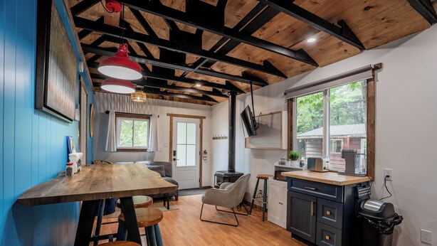 Una cocina moderna con vigas de madera, un ventanal grande y un comedor con taburetes.