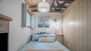 Un dormitorio con cama, un cuadro, una lámpara y paneles de madera.