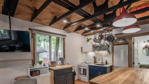 Una cocina compacta con techo de madera, un ventanal grande y una zona de comedor con mesa de madera.