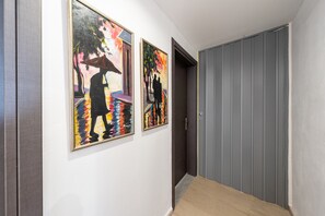 A hallway with two framed paintings on the wall, a door, and a grey sliding door. - Room 'Relaxroom 1' with Shared Garden, Wi-Fi and Air Conditioning (Lefkimmi)