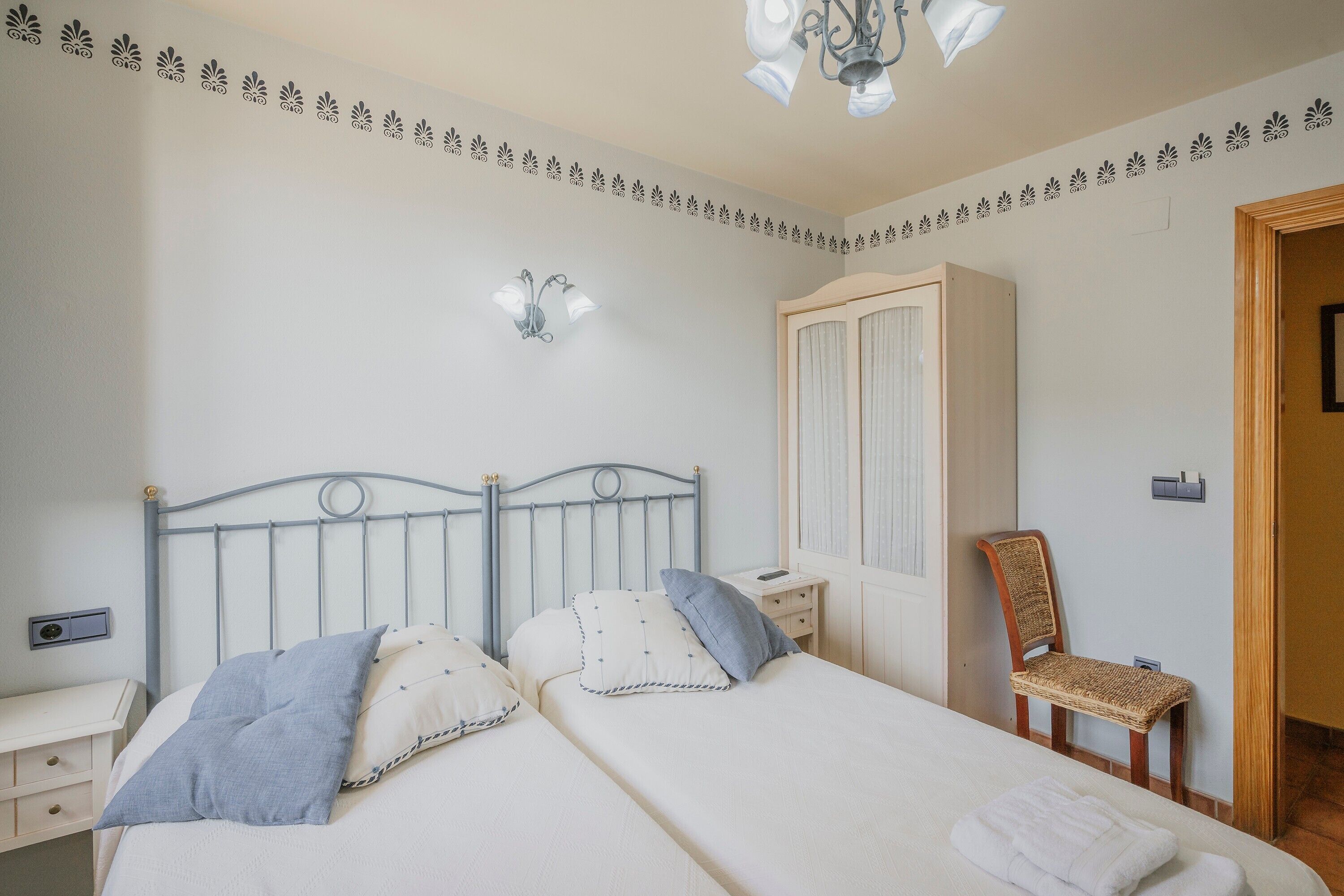 Een slaapkamer met een bed, nachtkastjes, een stoel, een kledingkast en een wandlamp.