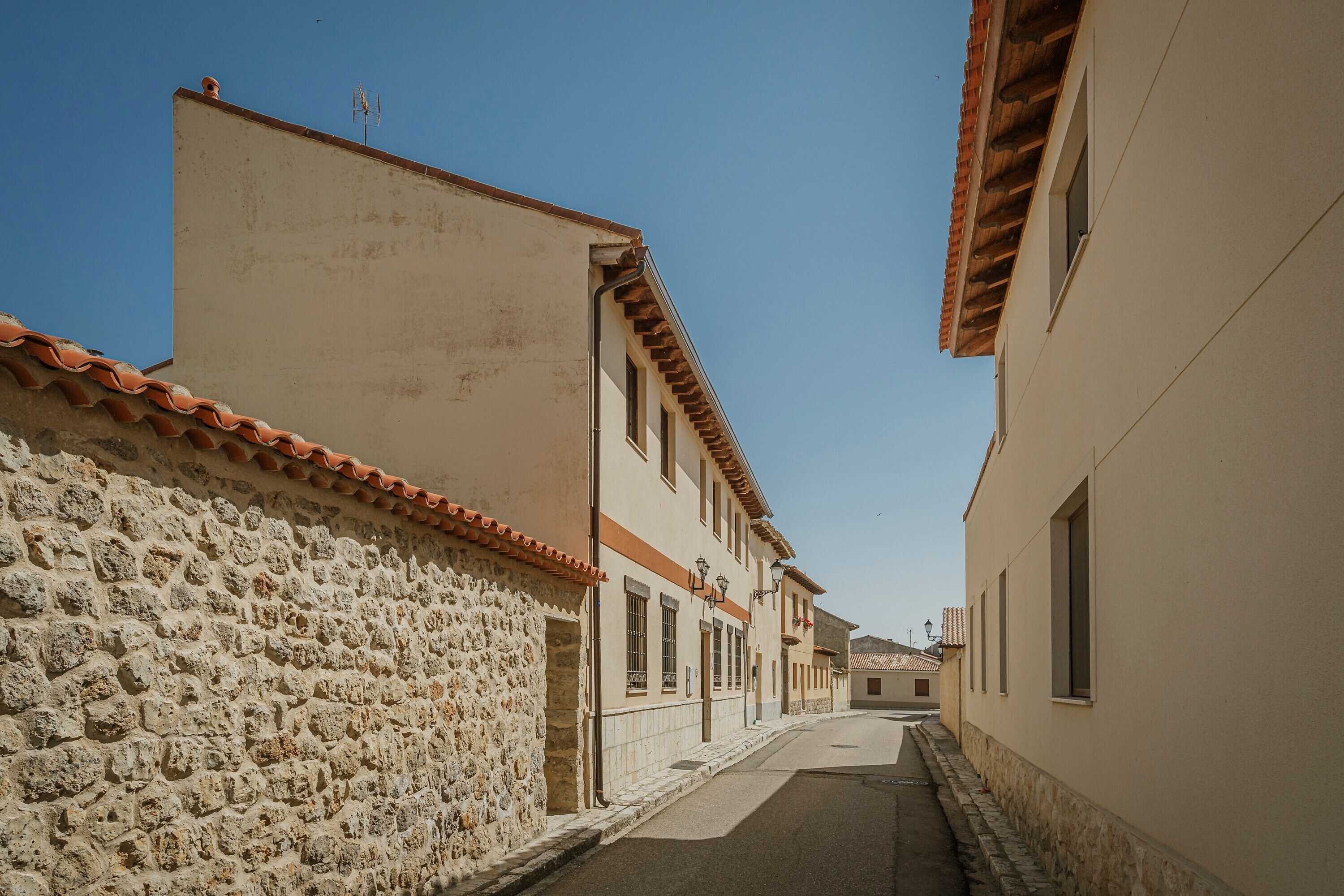 Un estrecho callejón flanqueado por edificios, con muros de piedra y techos de tejas.