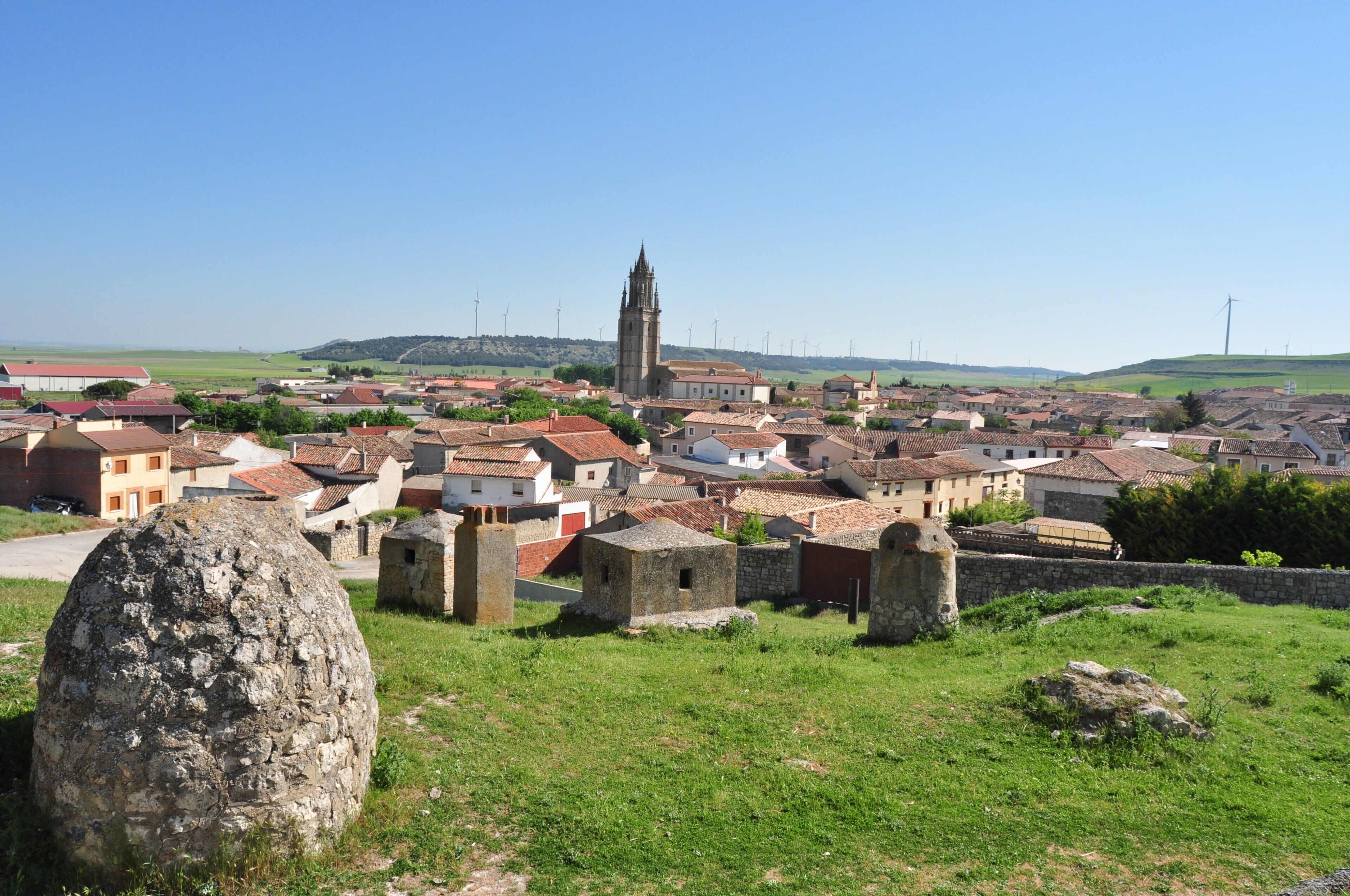 Une ville historique, caractérisée par un imposant clocher d’église, des bâtiments en pierre et un grand rocher en premier plan.