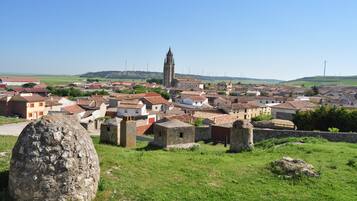 Une ville historique, caractérisée par un imposant clocher d’église, des bâtiments en pierre et un grand rocher en premier plan.