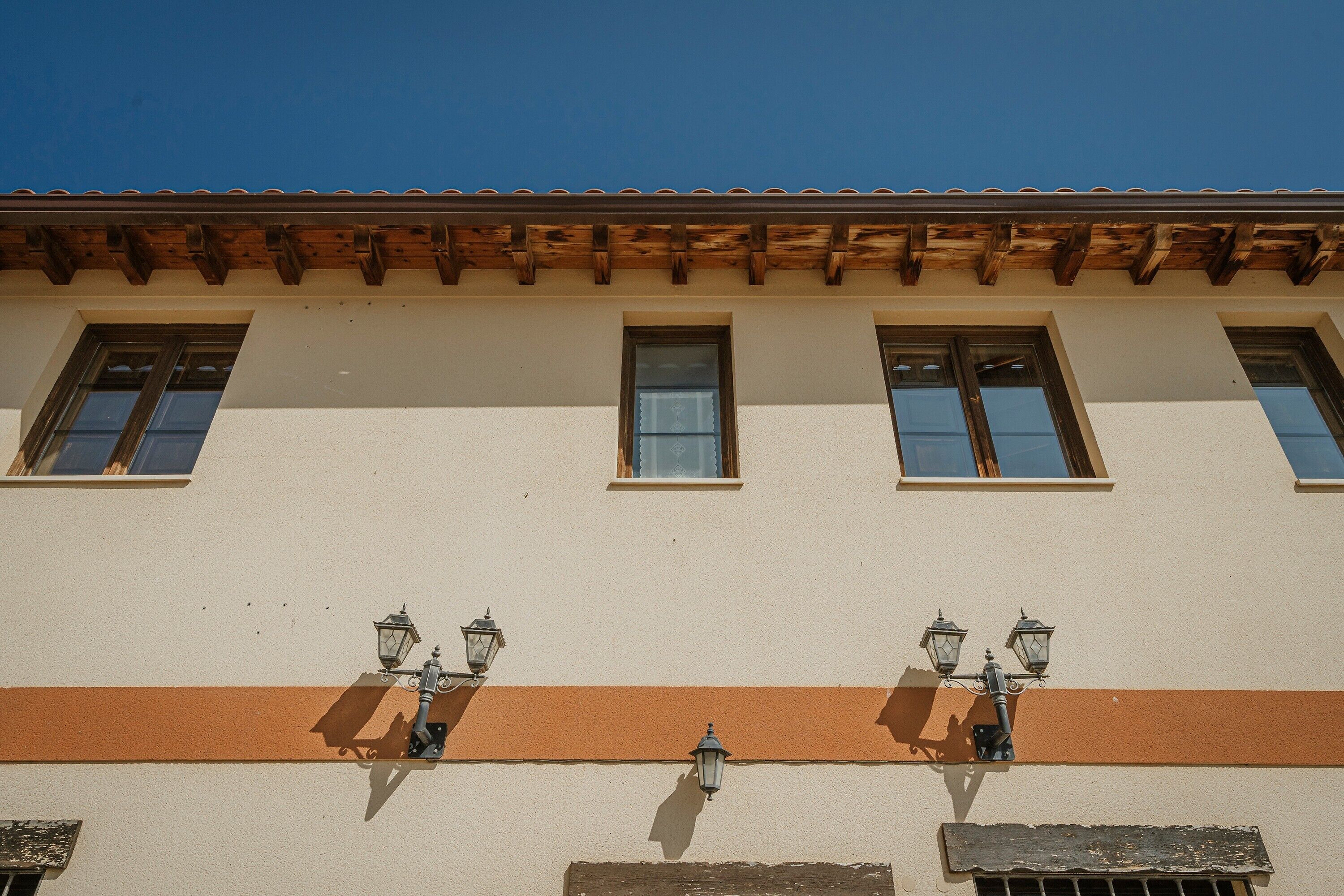 Um edifício com fachada plana, várias janelas e teto de madeira.